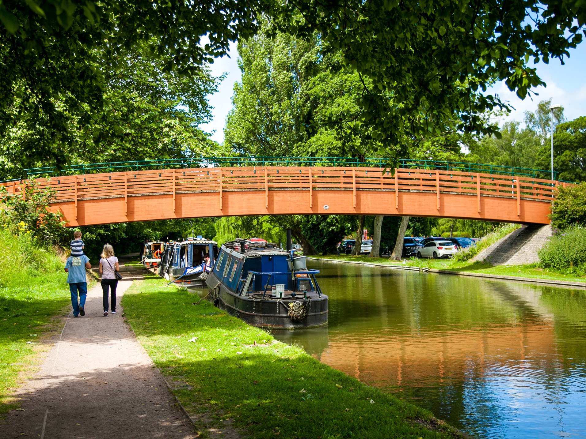 Canal & River Trust - Legacy Engagement & Development. A young family walking along a canal path by a newly develped footbridge on a warm and bright day.