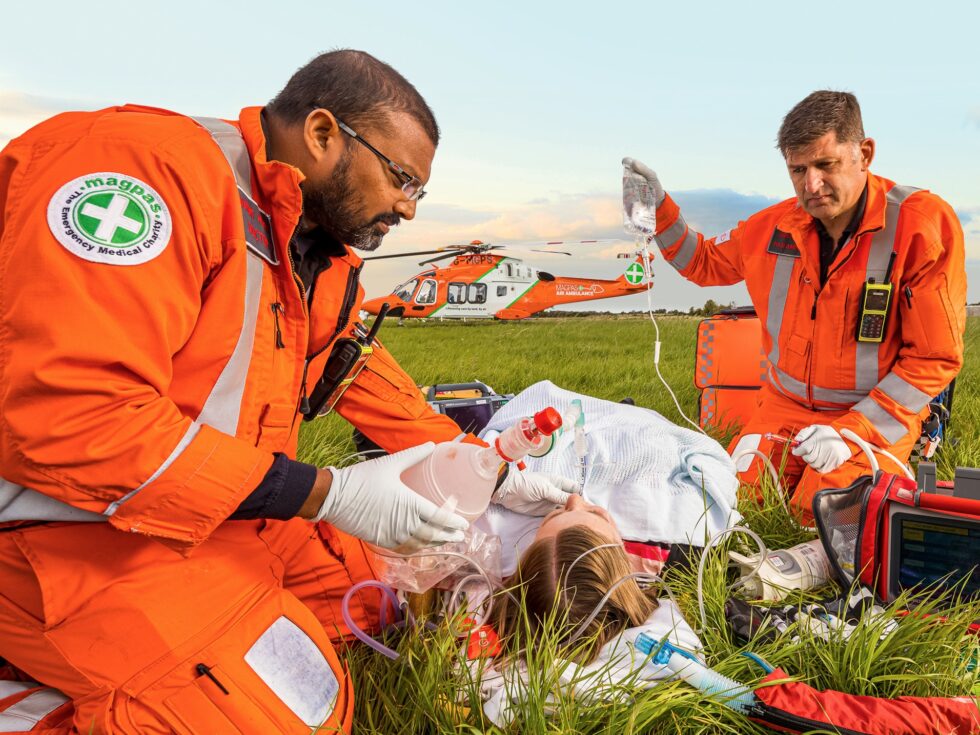 MAGPAS Air Ambulance - Building a Brand to Fly Higher. A MAGPAS orange, white and green medical helicopter hovering in mid air.