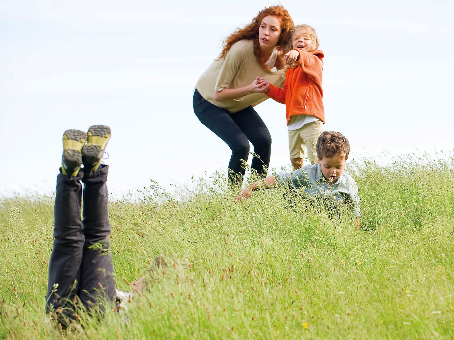 PACEY - Building bright futures. A young family playing on a hill side, with one young boy stood with his mum while pointing down the hill.